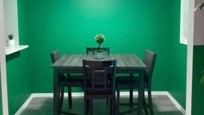 A dining area with a green wall, a wooden table, four chairs, and a small potted plant. - Sale!!! Emerald Grande family home (Atlanta)
