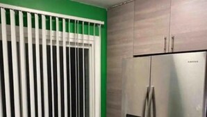 A kitchen with a stainless steel refrigerator, a green wall, and a window with white blinds. - Sale!!! Emerald Grande family home (Atlanta)