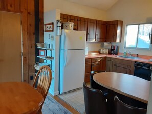 Eine kompakte Küche mit Holzausstattung, einem Kühlschrank, einer Spüle und einem Essbereich mit Tisch und Stühlen.