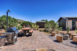 An outdoor patio with a grill, picnic table, and fire pit.