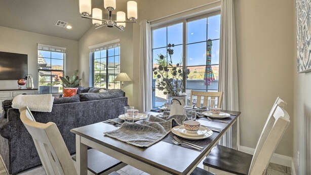 A dining area with a table set for four, a sofa, and a large window with curtains. - Washington Townhome w/ Patio + Resort Perks! (Washington)