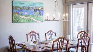 A dining area with a table set for six, wooden chairs, a chandelier, and a painting on the wall. - Riverfront hidden gem, ground floor open space! (Madison Heights)