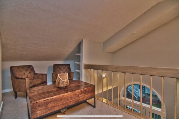 A spacious balcony with a wooden railing, a brown leather sofa, and a wooden coffee table.