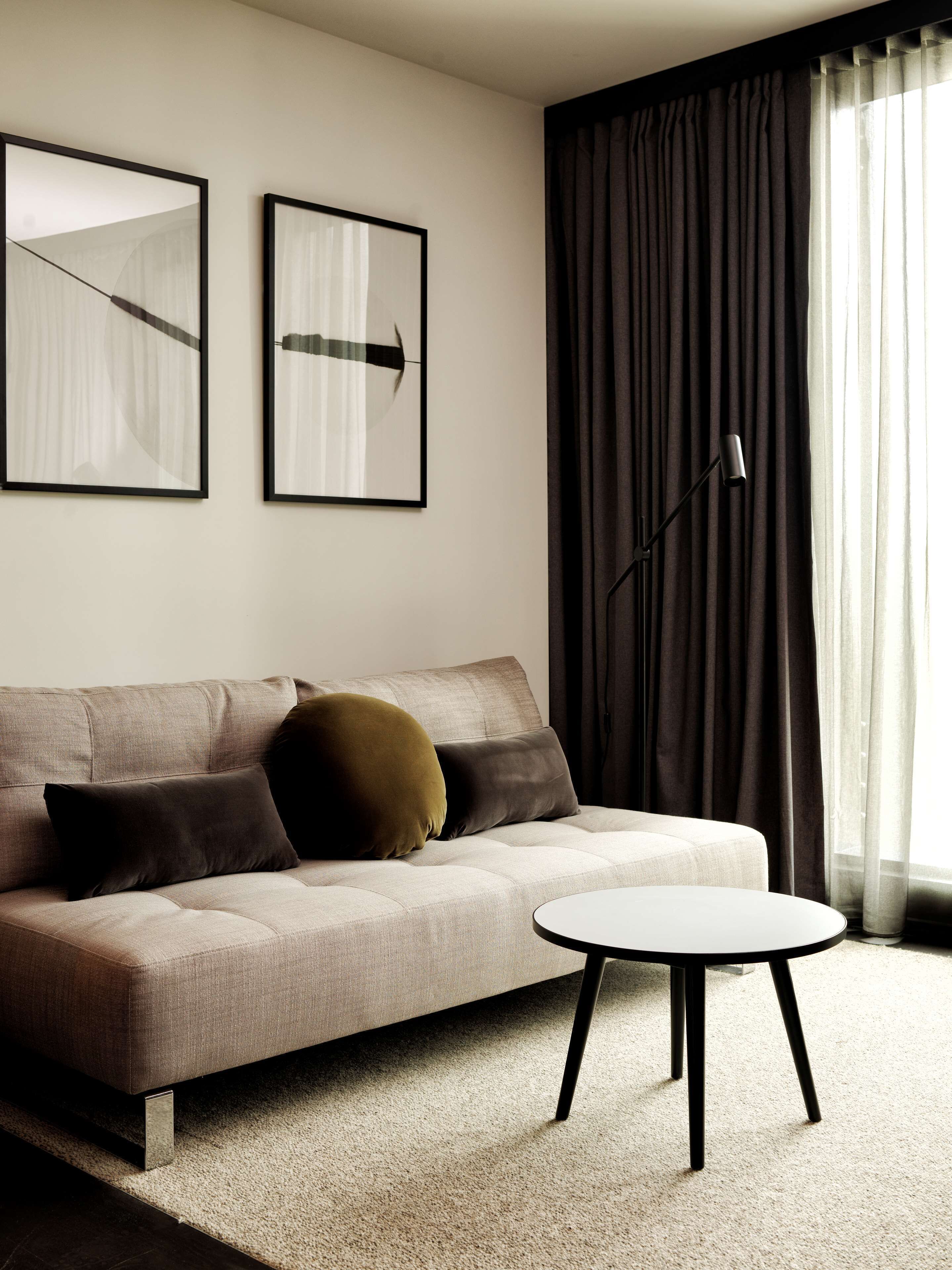 A modern living room with a sofa, two pillows, a floor lamp, and a small round table.