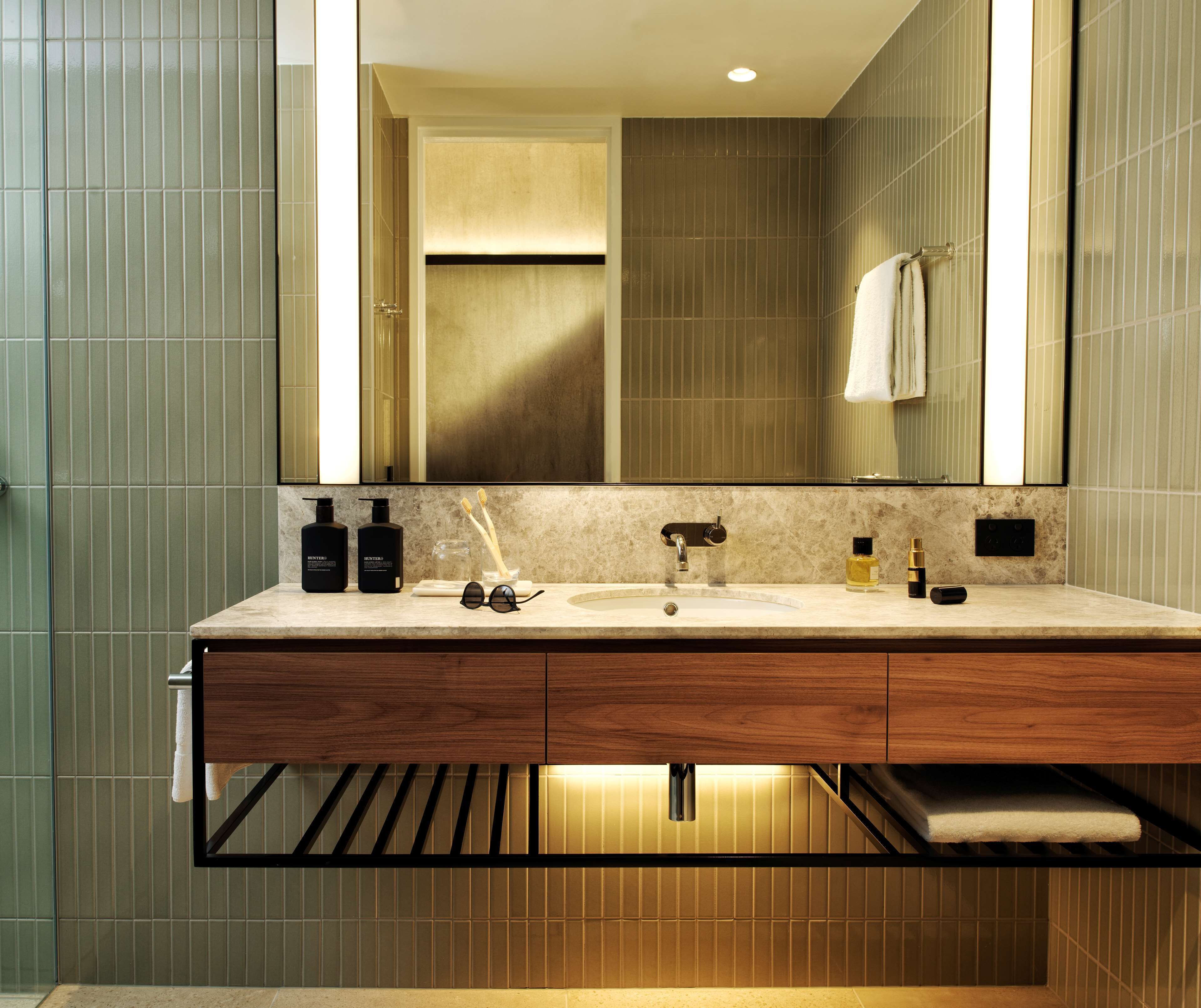 A modern bathroom with a large mirror, a sink, and a towel rack.