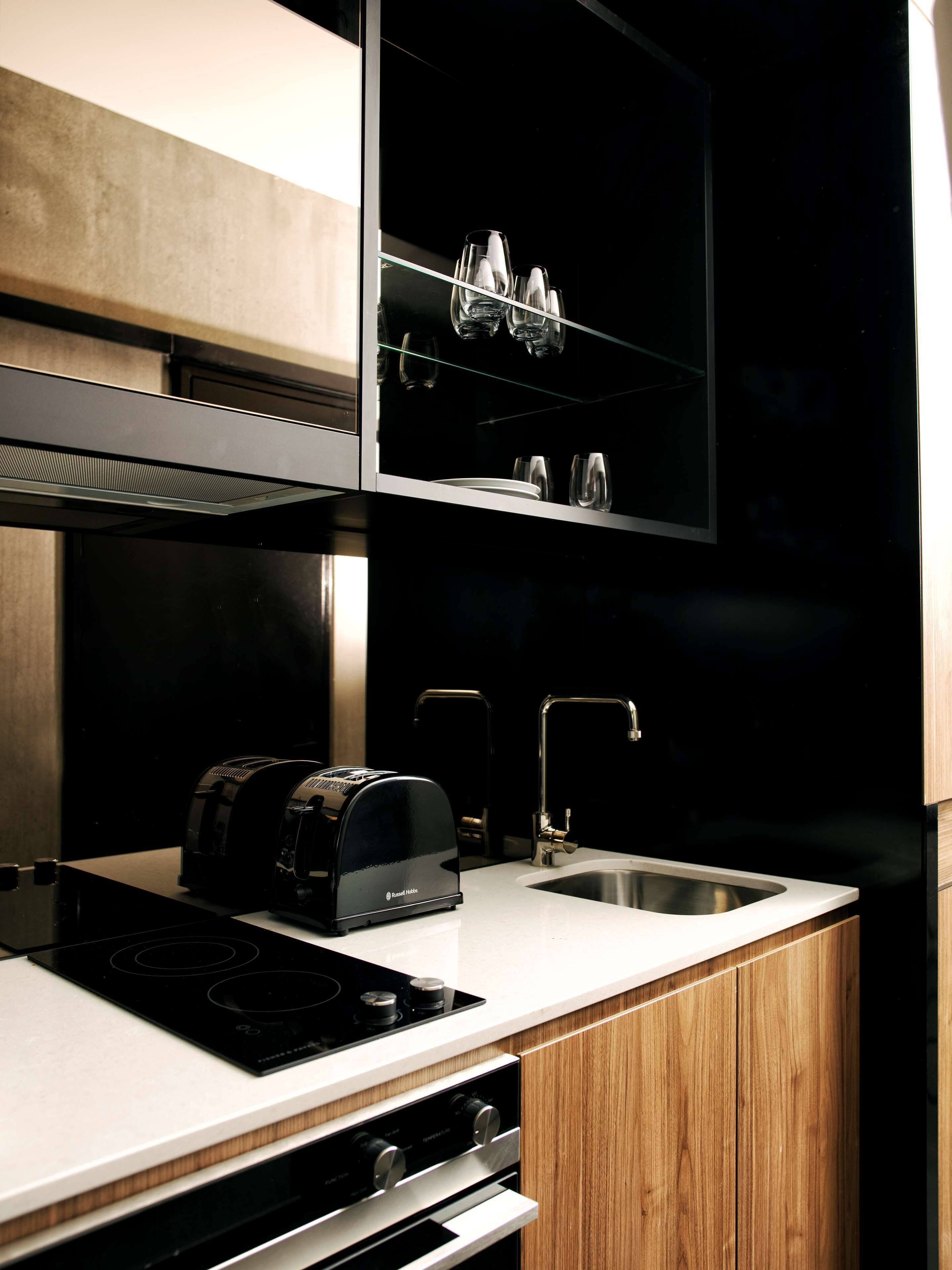 A modern kitchen with a built-in toaster, a sink, and a glass cabinet above the counter.