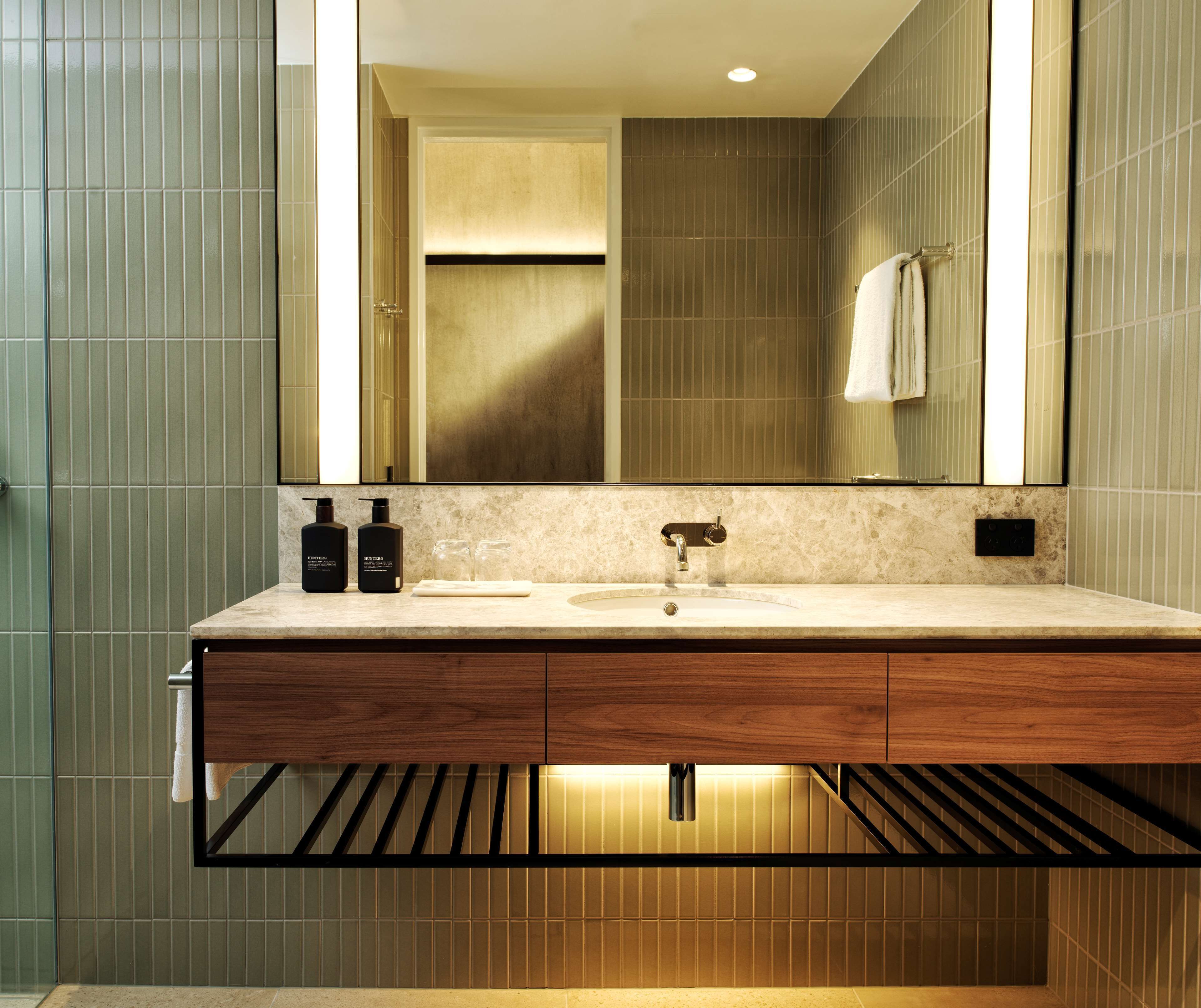 A modern bathroom with a wooden vanity, a large mirror, and a towel rack.