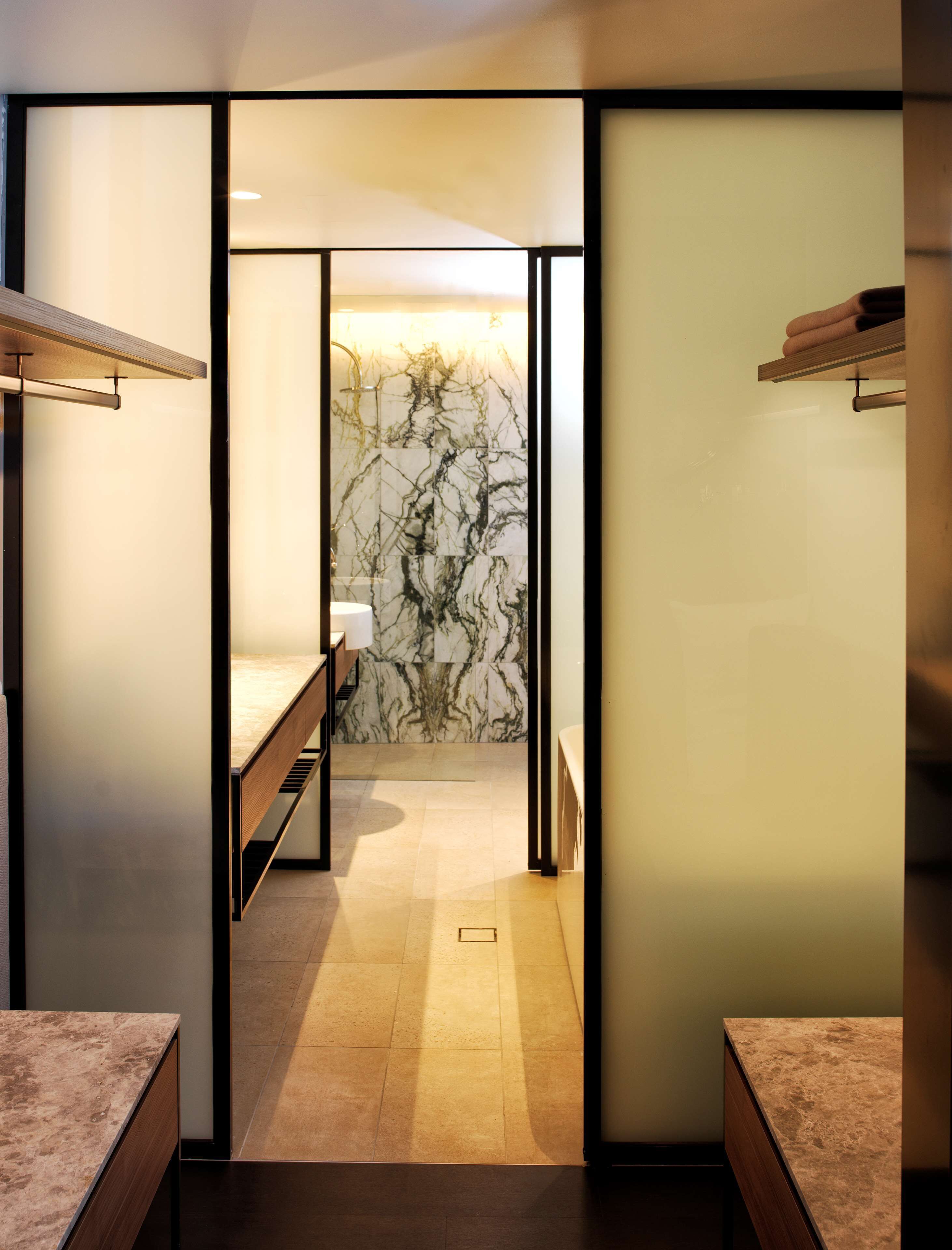Un bagno moderno con una parete in marmo, un lavandino e uno specchio.