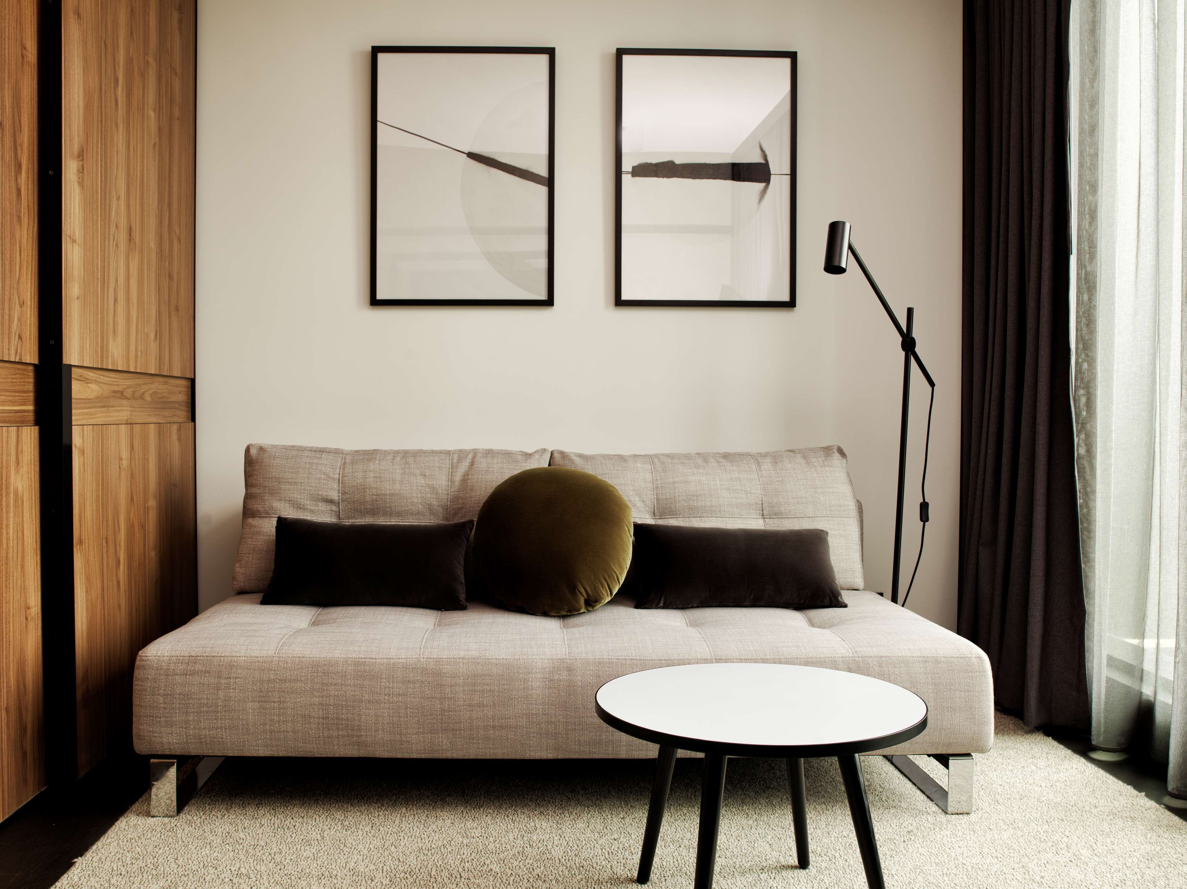 A modern living room with a sofa, two framed abstract artworks, a floor lamp, and a small table.