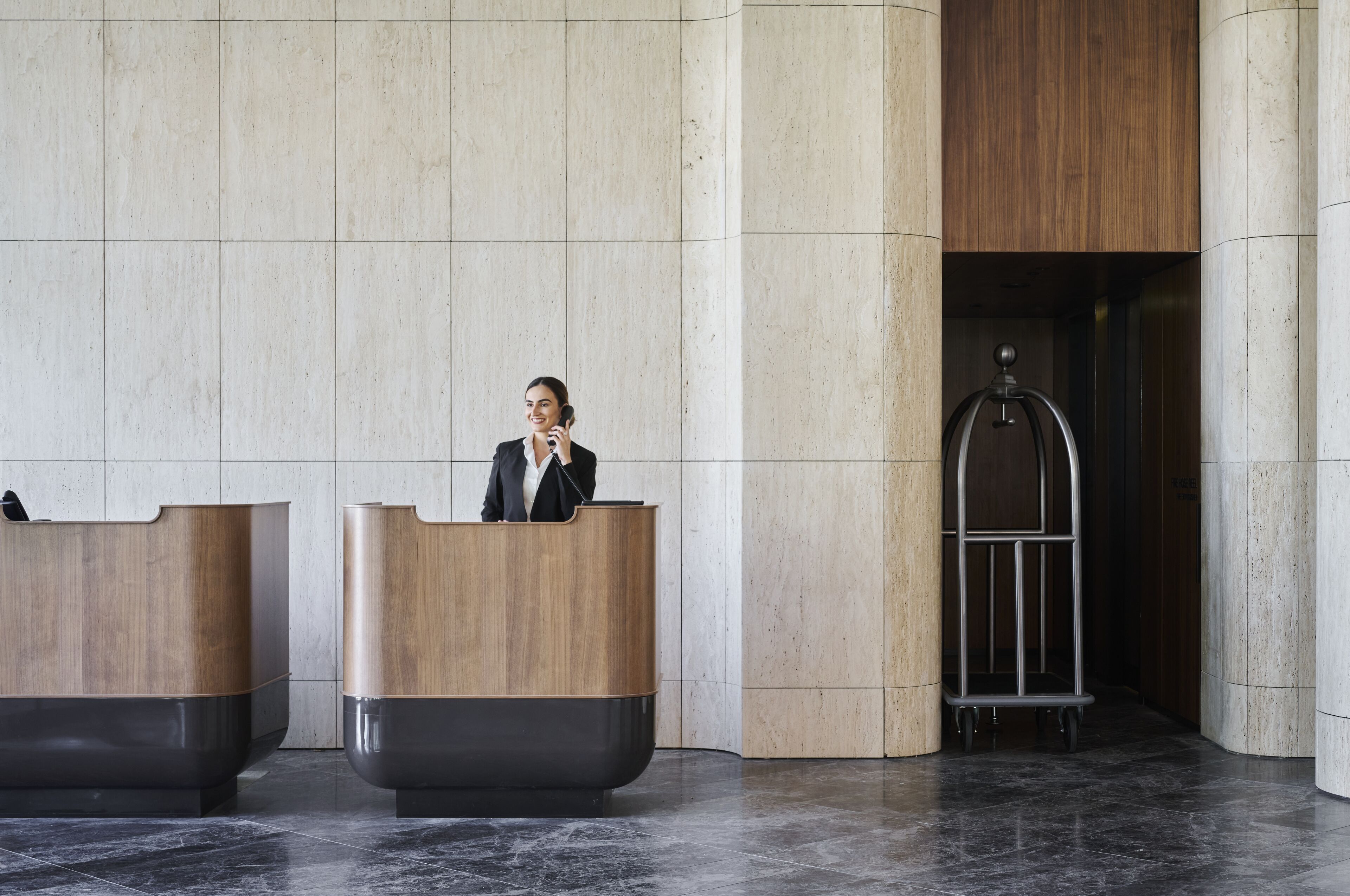 A reception area with two wooden reception desks and a metal elevator.