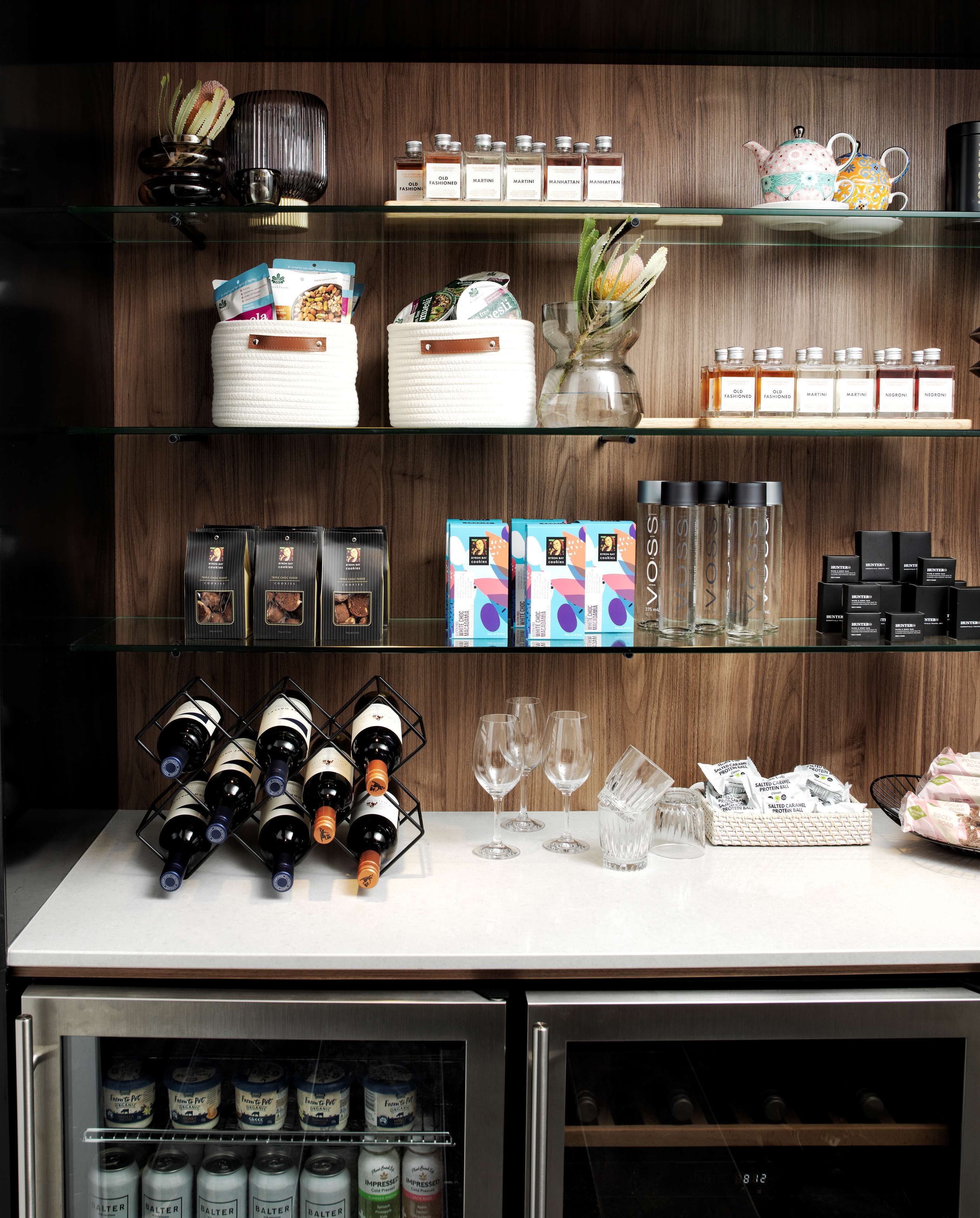 A bar area with shelves stocked with various bottles, glasses, and condiments.