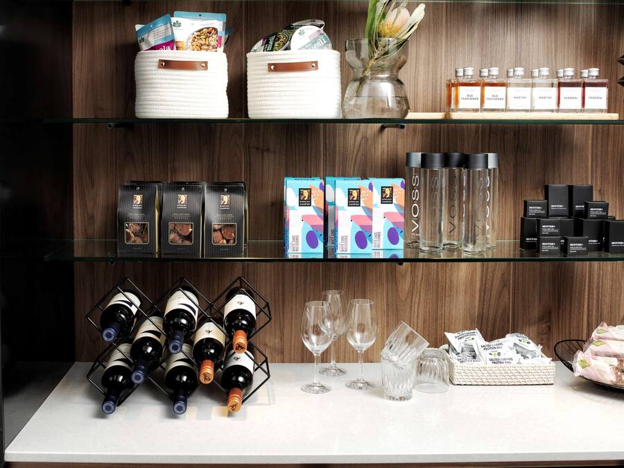 A bar area with shelves stocked with various bottles, glasses, and condiments.
