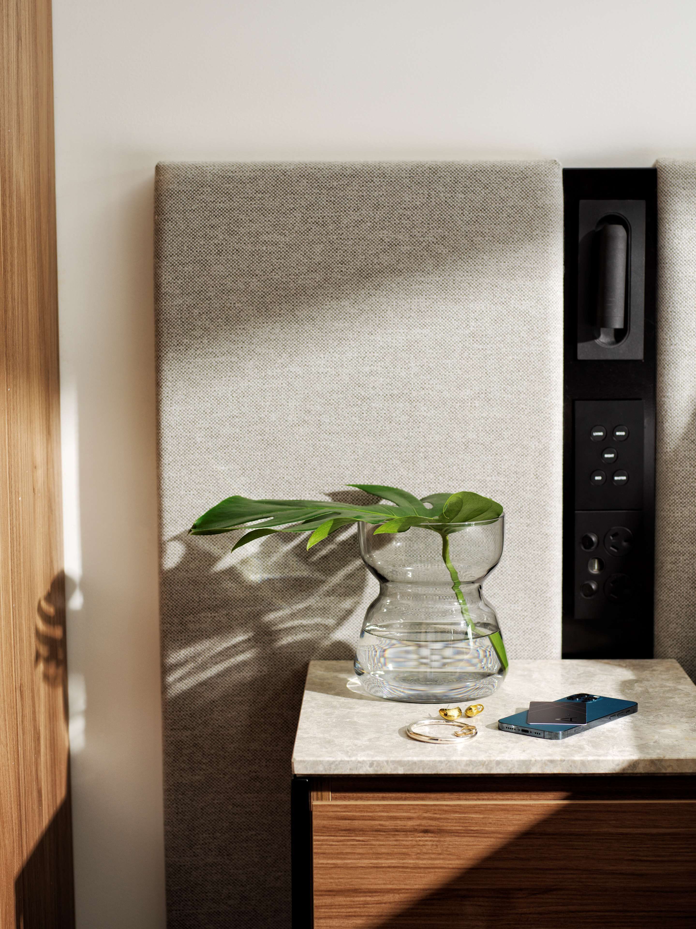 Ein modernes Zimmer mit minimalistischem Design, ausgestattet mit einem Holzkasten, einer Marmarbeplatte und einer wandmontierten Steuerung.
