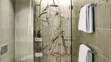 Un baño moderno con ducha de vidrio, paredes de mármol y un perchero para toallas.