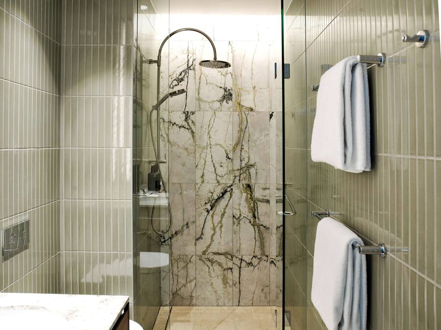 Un baño moderno con ducha de vidrio, paredes de mármol y un perchero para toallas.