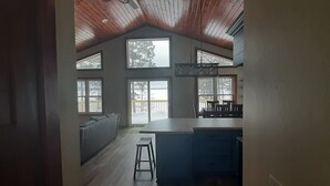 Una cocina amplia con una isla grande, múltiples ventanas y un techo alto con vigas a la vista.