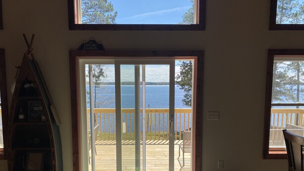 Una habitación con un amplio ventanal corredera que da a una terraza con vistas a un lago.