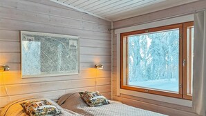 Una stanza accogliente con due letti, un'ampia finestra con vista innevata e una mappa incorniciata al muro.