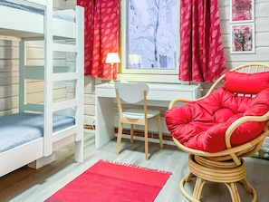 A room with a bunk bed, a desk, a chair, and a window with curtains.