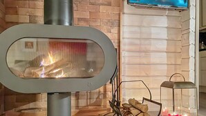 Un caminetto moderno con un pannello di vetro trasparente, una TV fissata alla parete e una lanterna a terra.