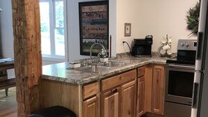 A modern kitchen with wooden cabinets, a stainless steel refrigerator, and a granite countertop.