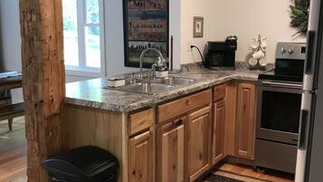 Una cocina moderna con armarios de madera, un refrigerador de acero inoxidable y una encimera de granito.