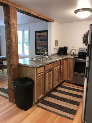 A modern kitchen with wooden cabinets, a stainless steel refrigerator, and a granite countertop.