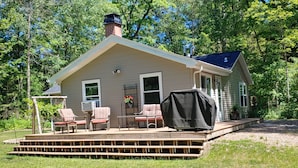 A house with a covered porch, a chimney, and a deck with chairs.
