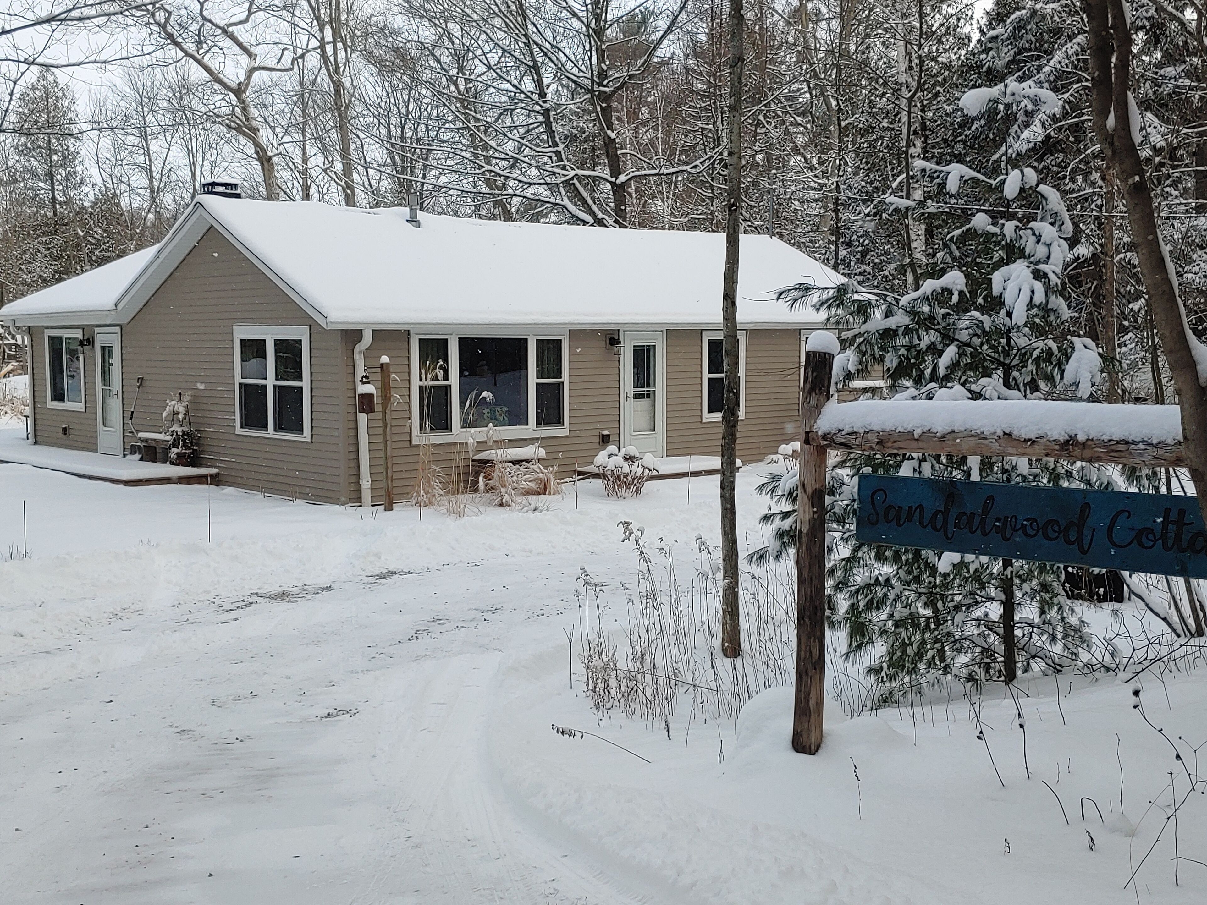Une maison de plain-pied, dont le toit est recouvert de neige et qui possède un porche bien visible.