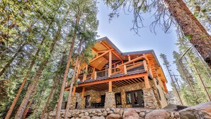 A log cabin with a stone foundation, wooden deck, and multiple balconies.