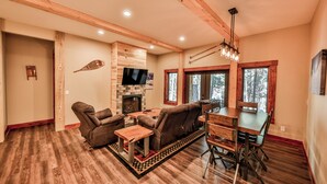 A spacious living room with a fireplace, a television, and a dining area with a wooden table and chairs.