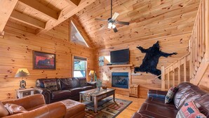 Een gezellig cabin interieur met houten wanden, een open haard, lederen meubels en een opgehangen dierenhuid.