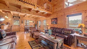 Een gezellig cabin interieur met houten wanden, een eethoek, een woonkamer met lederen meubels en een vide.