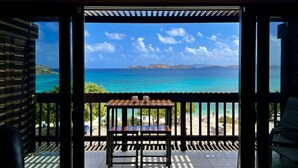 Ein Balkon mit Tisch und Stühlen mit Blick auf einen Strand und das Meer.