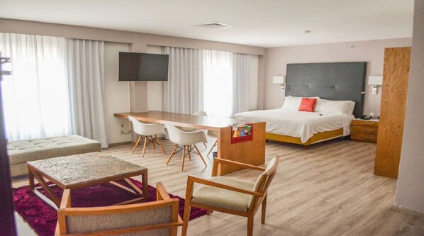 A hotel room with a bed, a desk, two chairs, a TV, and a small table. - Mision Irapuato (Irapuato)