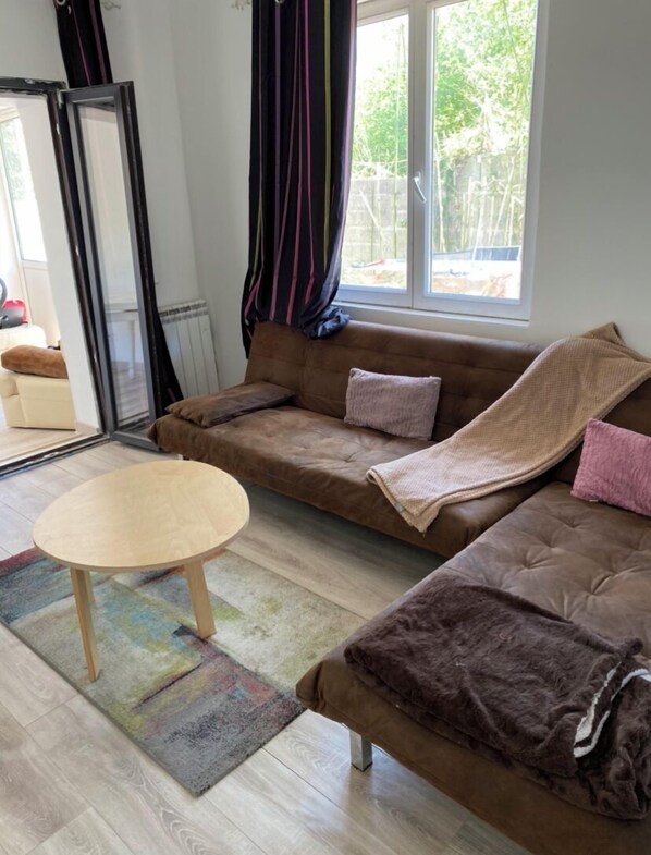 A cozy living room with a brown sofa, a small wooden table, and a colorful rug.