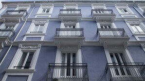 A multi-story building with a symmetrical facade, featuring evenly spaced windows and ornate white trim. - Flats Friends Soho Suites (Valencia)
