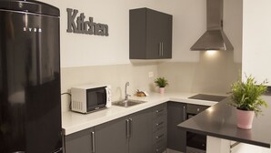 A modern kitchen with a black refrigerator, a microwave, a sink, and dark cabinets. - Flats Friends Soho Suites (Valencia)