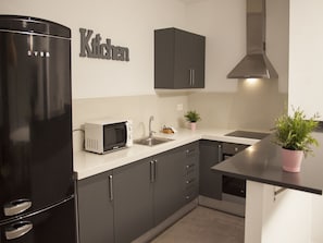 Una cocina moderna con un refrigerador negro, un microondas, un fregadero y gabinetes oscuros.