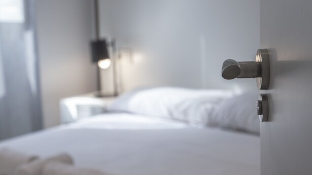 A modern bedroom with a neatly made bed, a bedside table with a lamp, and a headboard. - Flats Friends Soho Suites (Valencia)