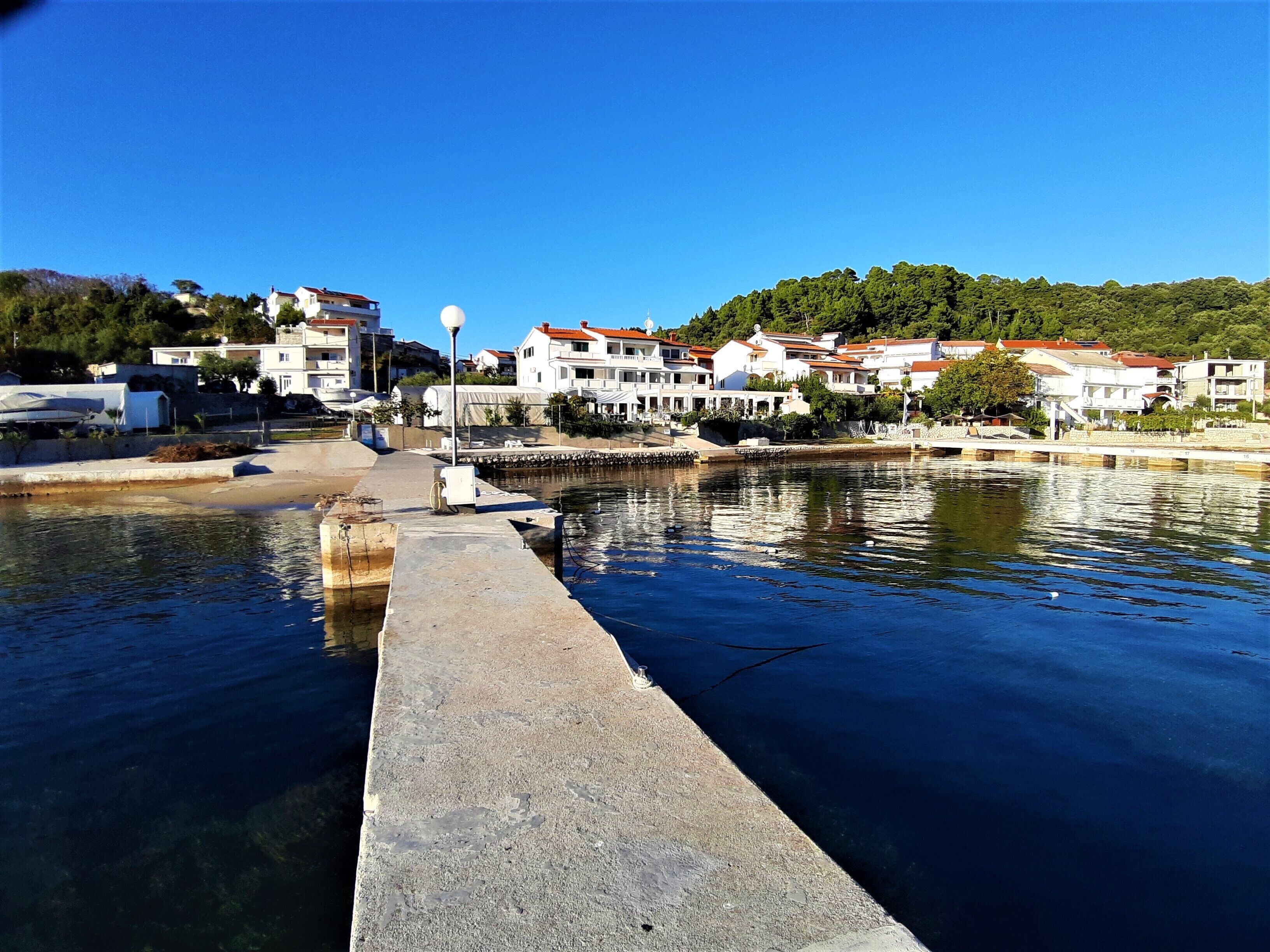 Eine Uferpromenade mit Gebäuden, blauem Himmel und ruhigem Wasser.
