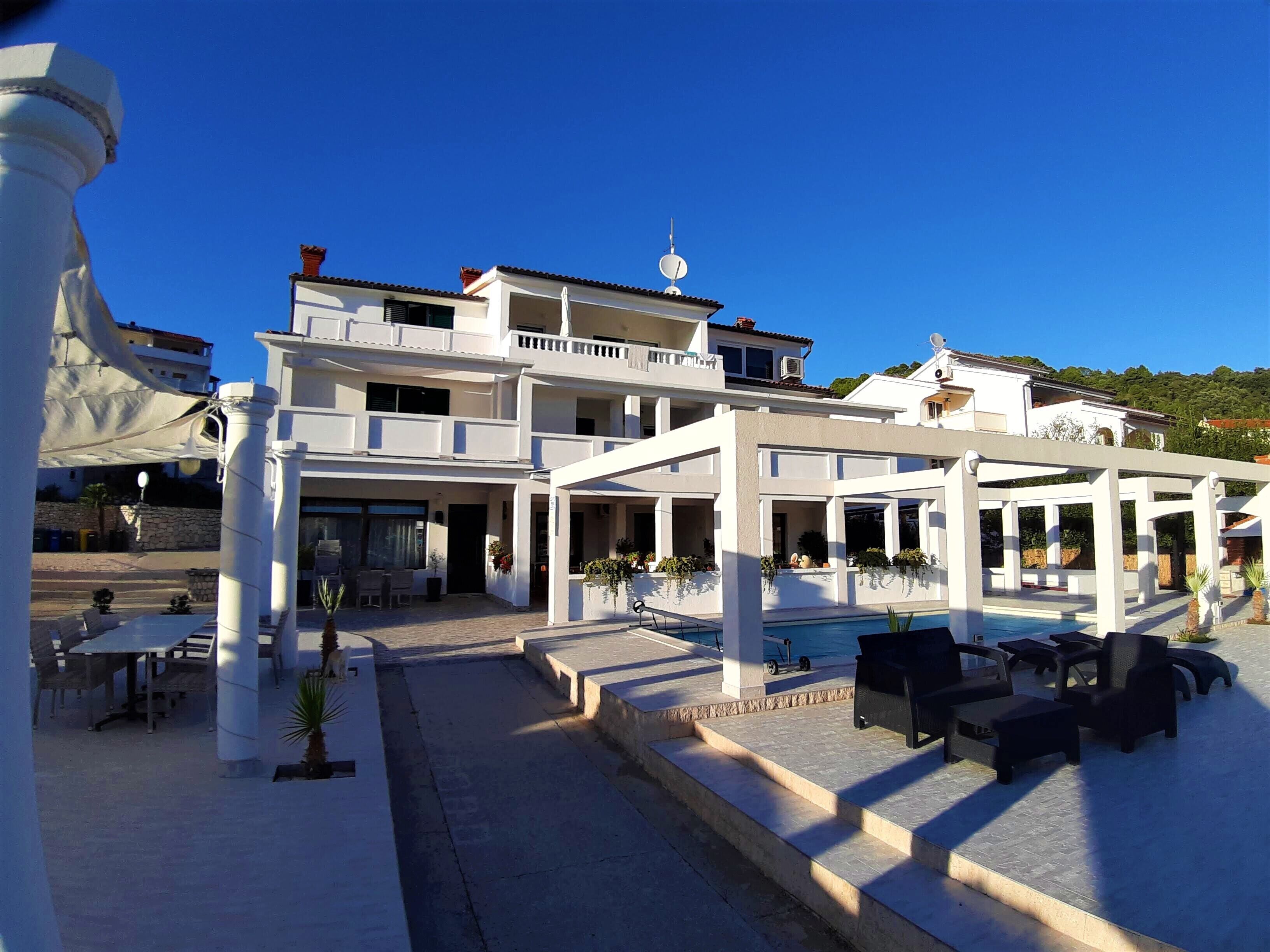 Un hotel de varios pisos con terraza exterior y zona de piscina.