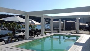Ein Poolbereich mit Liegestühlen und Sonnenschirmen, umgeben von einer weißen Pergola.