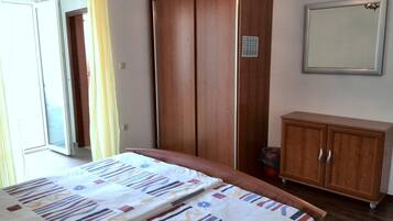 Un dormitorio con cama, armario, aparador y espejo.