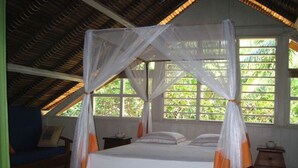 A room with a bed under a canopy, large windows, and a wooden ceiling.