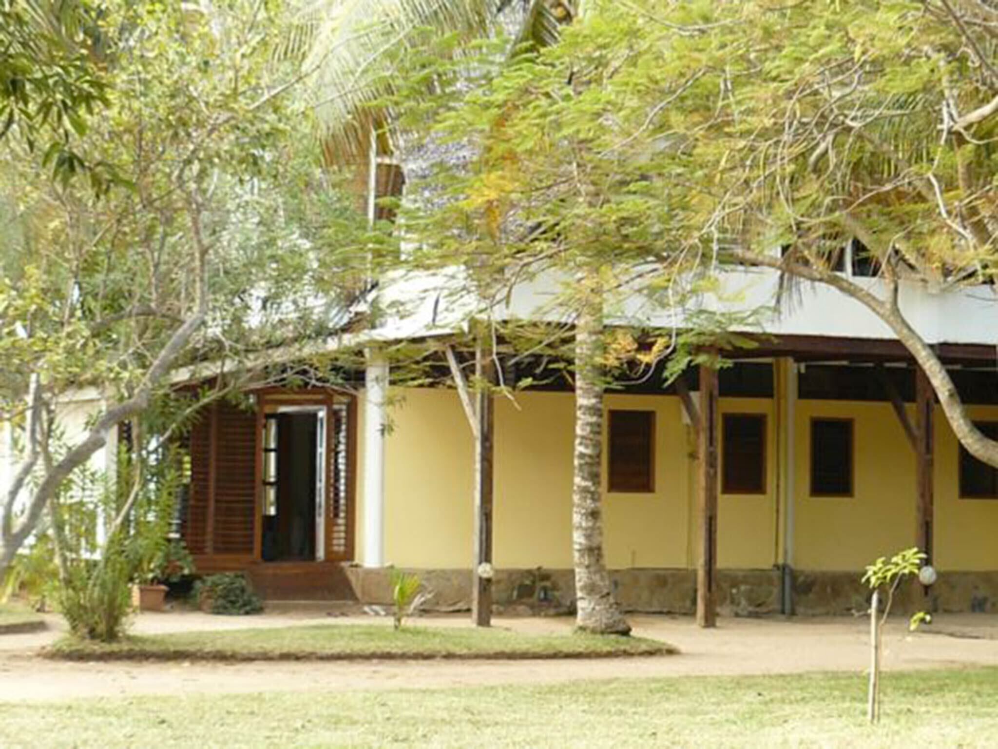 A two-story building with a yellow facade, wooden shutters, and a covered porch.