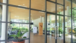 Een sportschool met trainingsapparatuur, een bordje voor de fitnessruimte en grote ramen voor natuurlijk licht.