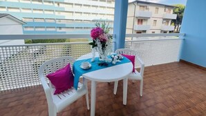 A balcony with a table set for two, white chairs, and a blue tablecloth. - Holiday in Bibione by the Beach-beahost (San Michele al Tagliamento)