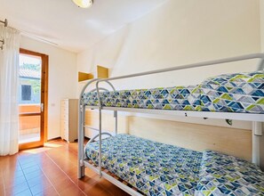 Une chambre avec un lit superposé, un bureau en bois et une fenêtre.