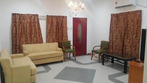 A living room with a sofa, two chairs, a table, and a TV. - Mri Homestay Sg Buloh - 2 Br House With Centralised Private Pool (Sungai Buloh)